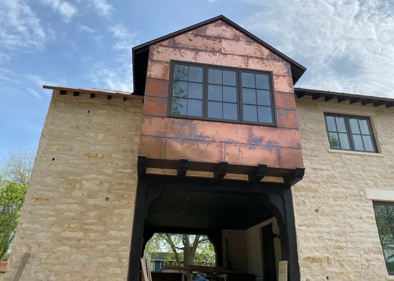 Copper metal panel facade on a stone building for Skylight Installation in Cheval