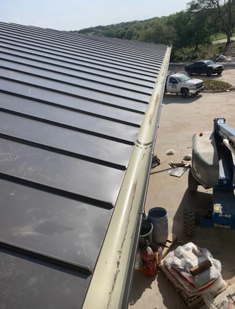 Standing seam panel and gutter detail on a metal roofing jobsite in Cheval